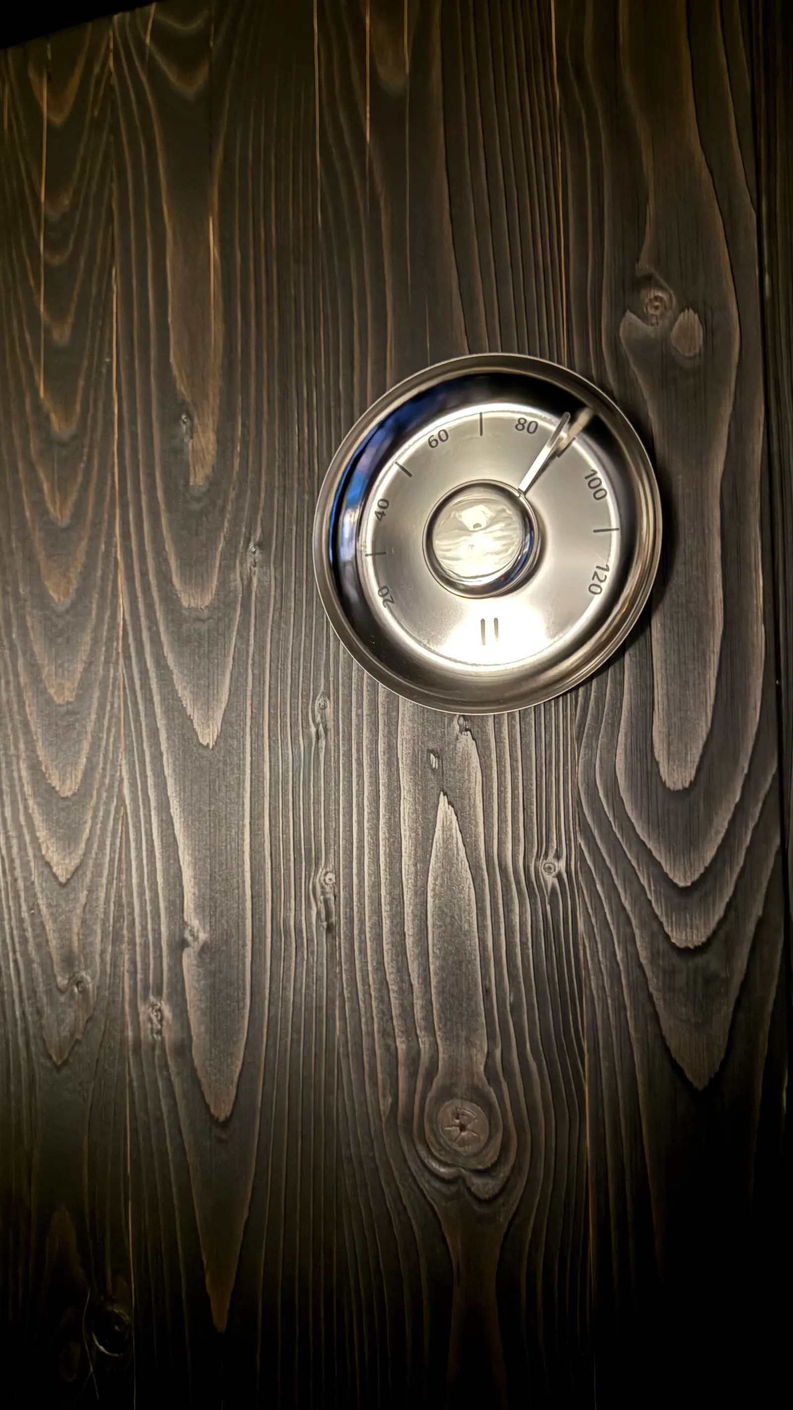 Teploměr na černém dřevěném obložení Secret Sauna